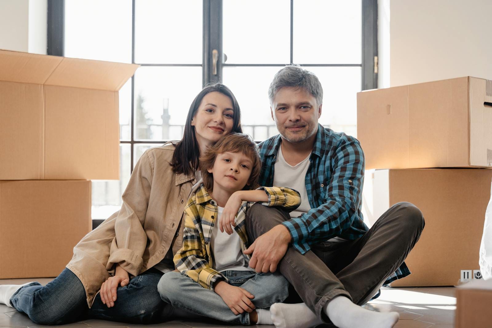 Happy family sitting together in their new home surrounded by moving boxes.