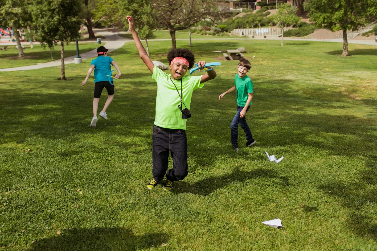 Kids having fun outdoors at summer camp playing with paper airplanes.