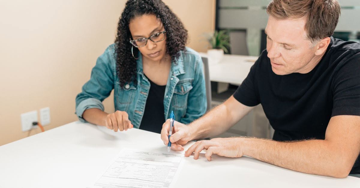 The Support System Behind Every Foster Parent in Pennsylvania A couple working together to sign important legal documents at a desk in an office setting.